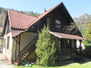 a small house with a brown roof and some trees at Holiday House Maluzina Low Tatras in Malužiná