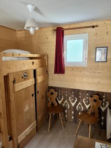 une chambre avec deux chaises, un lit et une fenêtre dans l'établissement Babaute 7, studio typique au pied des pistes, à Prémanon
