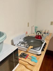 a kitchen counter with a stove with pans on it at Rosa - Private room in shared house in Roatan