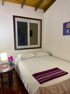 two beds in a room with a table and a window at Rosa - Private room in shared house in Roatan