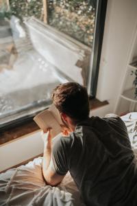 a man sitting on a bed reading a book at Horse Park Hideaway, Luxury Hot Tub Glamping Retreat in Pilling