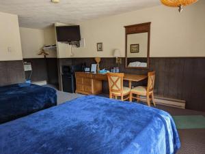 a hotel room with a bed and a desk and a table at Crossroads motel & cabins in Oxford