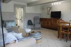 a living room with a couch and a tv at Gîte Fleurs de Gamay au coeur du Beaujolais in Lancié