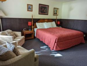 a bedroom with a large bed and two chairs at Crossroads motel & cabins in Oxford