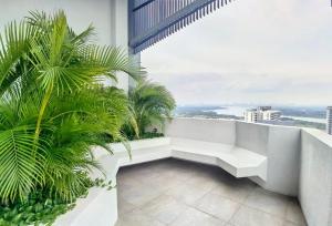 a white bench on a balcony with palm trees at C1110 Almas Suites Galaxy Space Netflix By STAY in Nusajaya