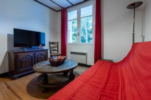Schlafzimmer mit einem roten Bett, einem Tisch und einem TV in der Unterkunft Chalet des Melezes in Font Romeu Odeillo Via