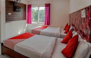 2 camas en una habitación de hotel con almohadas rojas en Amith Comforts, en Mysore