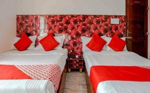 2 camas en una habitación con almohadas rojas en Amith Comforts, en Mysore