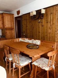 a wooden table with chairs and a wooden wall at Appartamento Il nido in Carisolo