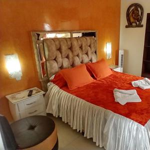 1 dormitorio con 1 cama grande con sábanas rojas y almohadas de color naranja en Posada Martha Tolima, en Salento