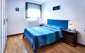 sypialnia z niebieskim łóżkiem i oknem w obiekcie Il Giacinto w Mediolanie