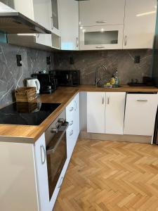 a kitchen with white cabinets and a wooden floor at Al Malina City Family Apt with Parking Space in Sofia