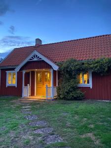 una casa roja con una puerta amarilla y un patio en Bo i egen stuga på härlig ölandsgård, en Köpingsvik