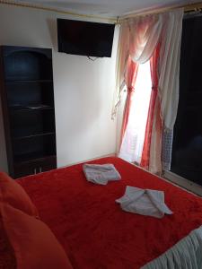 a bedroom with a red bed with two towels on it at Posada Martha Tolima in Salento