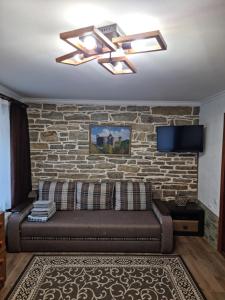 a living room with a couch and a brick wall at Kvartura z dvorukom in Kamianets-Podilskyi