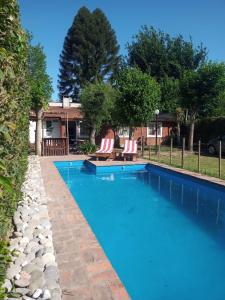 una piscina con 2 sillas y una casa en Quinta El Cholito en Luján