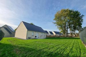 a large grassy yard with a white barn at Spacious modern house near the Golf of Ardrée in Saint-Antoine-du-Rocher