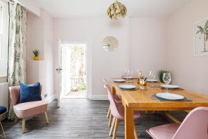 a dining room with a wooden table and pink chairs at Cloisters Cottage in Chichester