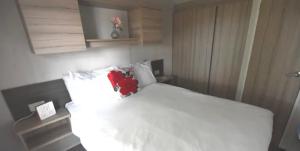 Schlafzimmer mit einem weißen Bett und einem roten Kissen in der Unterkunft MV18 Park Holidays, St Osyth Beach no smoking self catering holiday in Saint Osyth