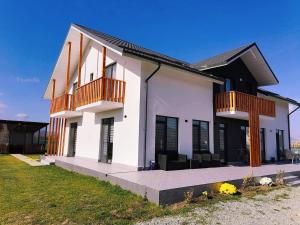 een wit huis met een balkon en een tuin bij CASA VIKI in Bănicel
