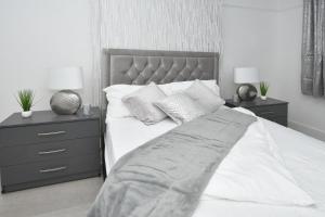 a bedroom with a bed with white sheets and pillows at Beautiful 3-Bed House by MiniStays Stoke-on-Trent in Stoke on Trent