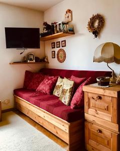 a red couch in a living room with a tv at Appartamento Il nido in Carisolo