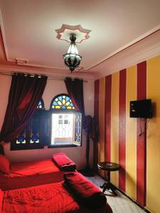 a bedroom with a red bed and a window at Hotel Sevilla in Chefchaouene