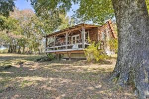 an old log house in the woods with a tree at Idyllic Cabin with Fire Pit, Kayak On-Site! in Bells