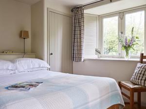 um quarto com uma cama, uma janela e uma cadeira em Yennadon Barn em Totnes