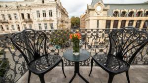 2 sillas y una mesa con un jarrón de flores en el balcón en TownHouse Tbilisi Boutique Hotel, en Tiflis