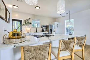 a kitchen with a large white counter with two chairs at Modern and Chic Gulfport Escape Walk to Beach! in Gulfport