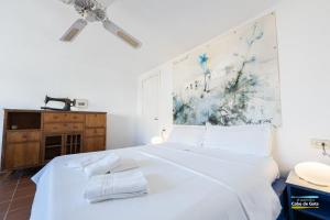 a bedroom with a white bed and a painting on the wall at CASA ESCUELA PLAYA in San José