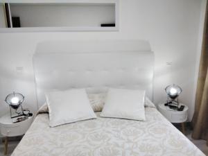 a white bedroom with two beds and two lamps at Albergue Piedad in Boó de Piélagos