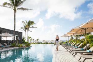 藍海灣的住宿－Anantara Iko Mauritius Resort & Villas，站在度假胜地游泳池边缘的女人