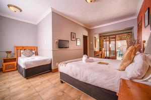 a hotel room with two beds and a television at The Palms Guesthouse in Nelspruit