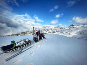 two people riding on a snowmobile in the snow at atipic lodge in Arette