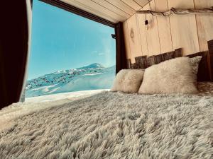 a bed with a view of a snow covered mountain at atipic lodge in Arette