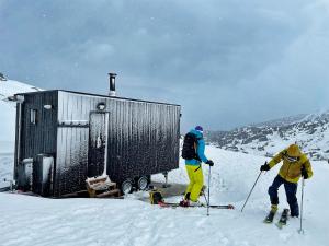 2 personnes à skis dans la neige à côté d'un bâtiment dans l'établissement atipic lodge, à Arette