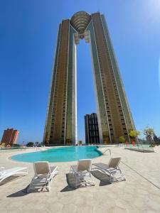 two tall buildings with chairs in front of a pool at Intempo Gold&Gris Apartment in Benidorm