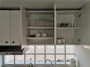 kuchnia z białymi szafkami, umywalką i oknem w obiekcie Costa Calma Sun & Pool Apartment w mieście Costa Calma