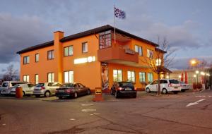 een oranje gebouw met auto's geparkeerd op een parkeerplaats bij Hotel Ganita Weil am Rhein in Weil am Rhein