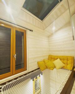 - un canapé jaune dans une chambre avec fenêtre dans l'établissement La Tiny Blue - maison insolite pour 2 - sans Tv, à Saint-Aignan