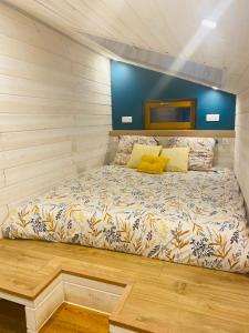 uma cama com almofadas amarelas num pequeno quarto em La Tiny Blue - maison insolite pour 2 - sans Tv em Saint-Aignan