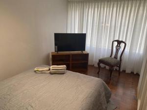 1 dormitorio con 1 cama, 1 silla y TV en Apartamento de lujo con jardines paisajísticos en La Paz