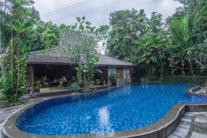 a swimming pool in front of a house with trees at Dream Village in Jarakan