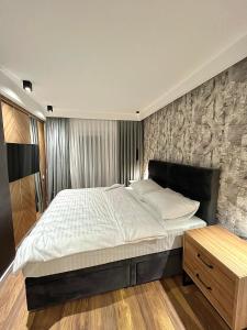 ブルチコにあるDelux Apartman PresidentBulevarの石壁のベッドルーム1室(大型ベッド1台付)