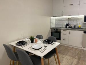 a kitchen with a white table and chairs with plates and glasses at Green park Sandanski in Sandanski