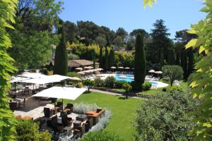 un giardino con tavoli e ombrelloni e una piscina di Hôtel De Mougins a Mougins