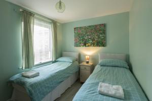 a bedroom with two beds and a painting on the wall at 1 Quayside Court in Swanage