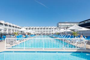 a large swimming pool with blue chairs and umbrellas at Grand Hotel Cape May in Cape May
